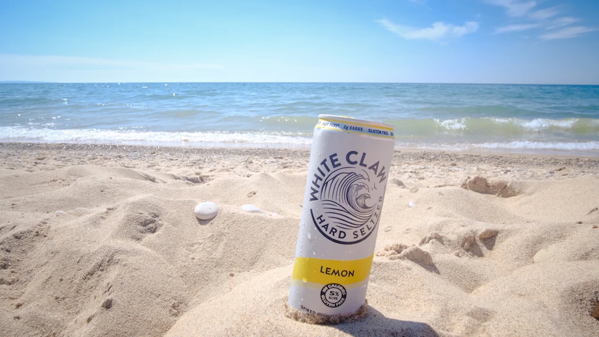 Picture of a gluten free White Claw cooler in the sand on the beach. 